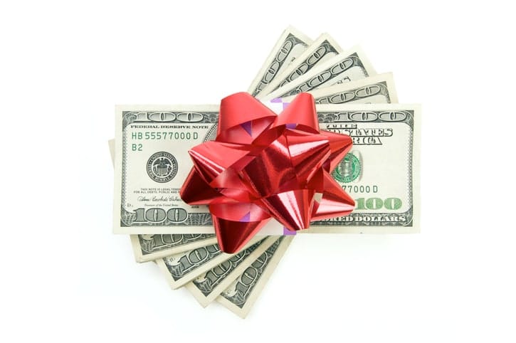 A stack of hundred dollar bills with a red bow on it to be used for gifts from our Holiday Club savings.