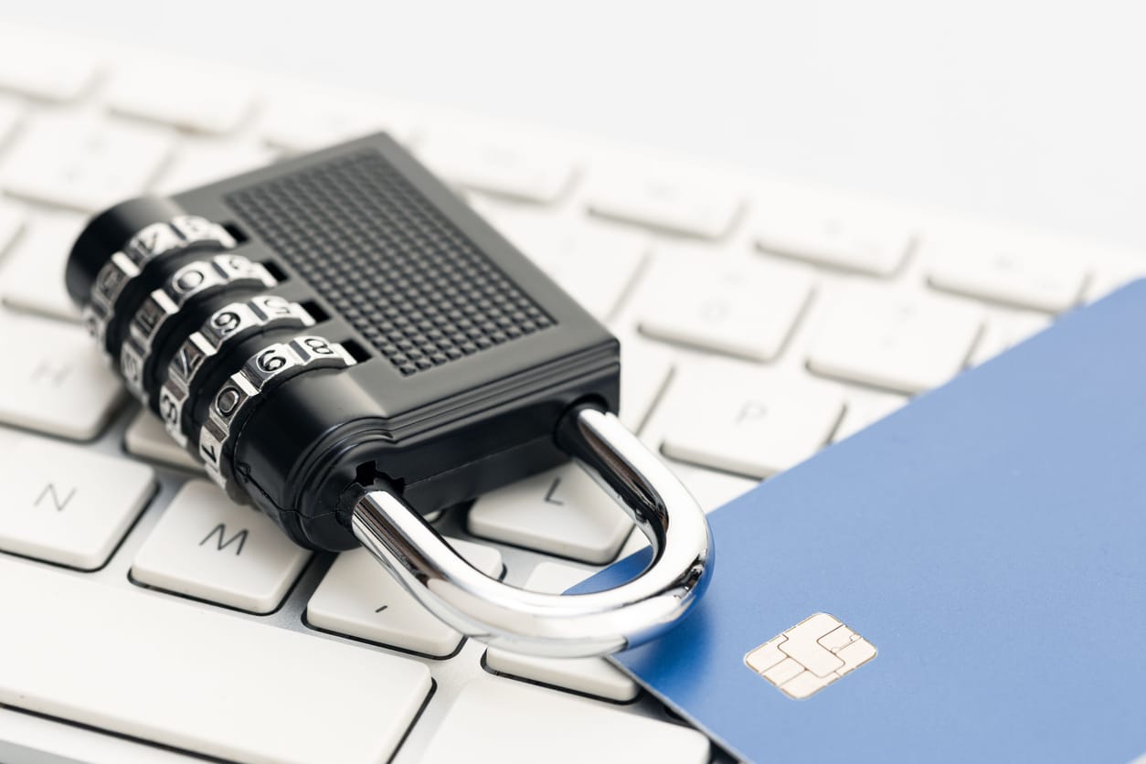 A combination lock and a credit card on a computer keyboard representing identity theft prevention.