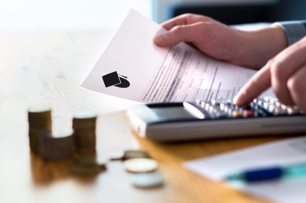 Man creating a college savings plan with a notebook and calculator on the table, preparing for future education costs.